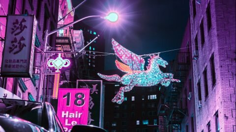 Light up unicorn hanging in amongst busy city nightlife