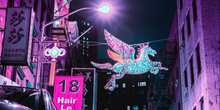 Light up unicorn hanging in amongst busy city nightlife