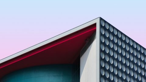 The corner of a building with a circle patterned side and blue face